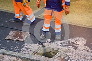 road workers and his truck cleaning the sewers on a road