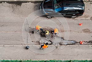 Road workers in orange vests repair the road. Pit removal and patching. View from above. works of replacing asphalt parts. Road