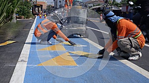 Road workers are painting teaffic on asphalt street