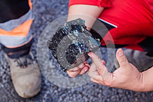 Road workers take a cube of asphalt