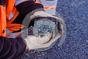 Road workers take a cube of asphalt