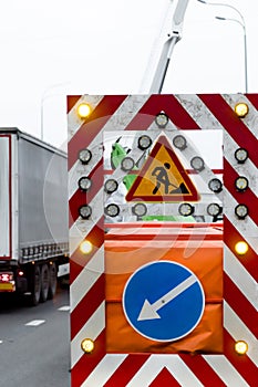 Road works, a big bright mobile sign with red white stripes, direction of the detour and a yellow flashing arrow on the trailer to