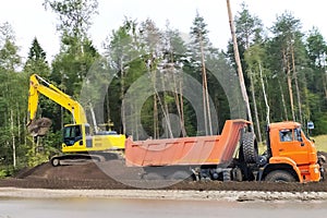 Road works, bulldozer and dump truck widen the road