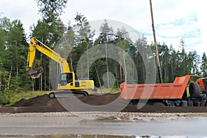 Road works, bulldozer and dump truck widen the road