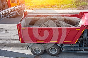 Road works. Dismantling of asphalt pavement. Recycled asphalt crumb is poured over the conveyor belt into the truck body