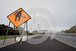 Road works oragne sign by a motorway. Construction and repair on a road warning. Transportation industry