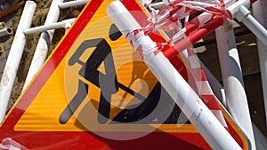 Road works sign denoting construction work and metal fencing on the ground. Close up. Red and yellow Ñolour.