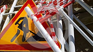 Road works sign denoting construction work and metal fencing on the ground. Close up. Red and yellow Ñolour. Restoration and reco