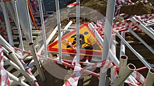 Road works sign denoting repair work and damaged broken metal fencing on ground. Construction site. Restoration and reconstruction