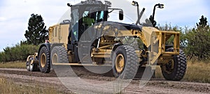 Roadgrader smoothing a dirt road.