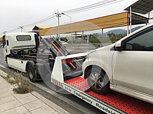 Roadside assistance broken car on a tow truck on a roadside