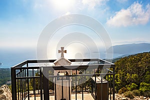 Roadside memorial with cross on hill over Aegean Sea bay Rhodes, Greece