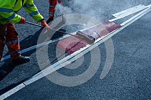 Roadworker applying thermoplastic road marking on the freshly laid tarmac during new roundabout