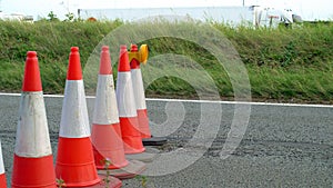 Roadworks cone flashing on UK motorway at evening with traffic passing
