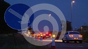 Roadworks cones flashing on UK motorway at night with traffic passing