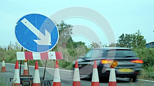 Roadworks cones flashing on UK motorway at night with traffic passing
