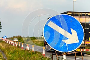 Roadworks directional arrow sign on UK motorway at evening with traffic passing