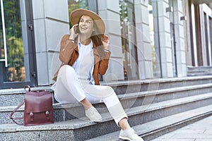 Roaming. Young happy female traveler or tourist wearing hat and backpack talking by phone with friend about vacation