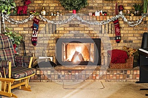 Roaring fire in a vinrage brick frieplace decorated for Christmas, with piano, rocking chair and cozy decor