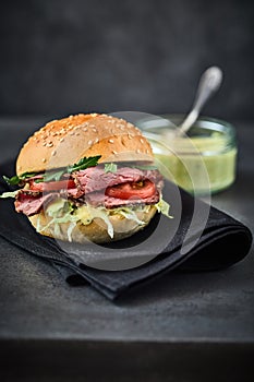 Roast beef pastrami sandwich with mustard in background