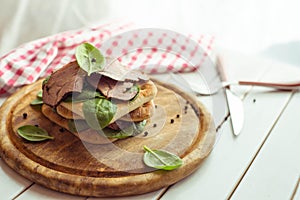 Roast beef sandwich with salad and pepper on rustic wooden plate. The toning.