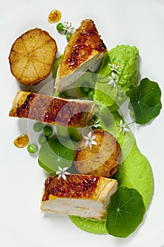 Roast chicken with fondant potatoes, pea mousse, pea puree, garlic flowers and nasturtium leaves