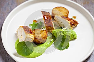 Roast chicken with fondant potatoes, pea mousse, pea puree, garlic flowers and nasturtium leaves