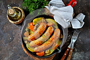 Roast Chicken sausages with potatoes, onions, carrots and mushrooms in a cast-iron pan. Top view.