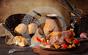 Roast chicken with vegetables and bread on the wooden table