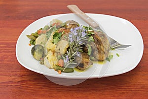 Roast chicken with vegetables and rosemary flowers