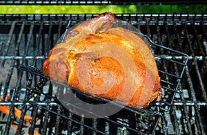 Roast of delicious roasted chicken on grill flaming charcoal