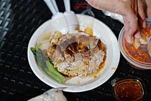 Roast duck rice in a foam plate on a black rattan table photo