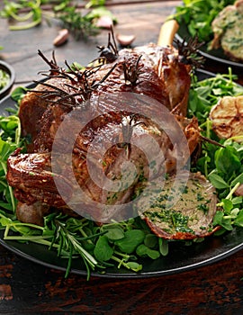 Roast Lamb leg with mint sauce, rosemary and garlic. on black plate, wooden table