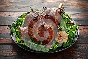 Roast Lamb leg with rosemary and garlic. on black plate, wooden table