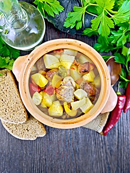 Roast meat and vegetables in clay pot on board top