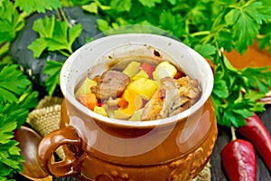 Roast meat and vegetables in pot on dark board