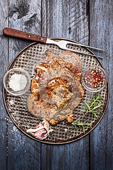 Roast pork with garlic, salt and red sauce on iron baking tray rusticwith fork on wooden rustic background, top view