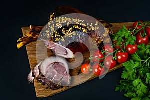 Roast pork knuckle and ingredients close-up on a slate board.