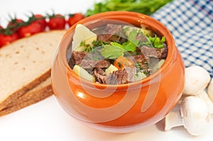 Roast in a pot with beef meat and potatoes on the table