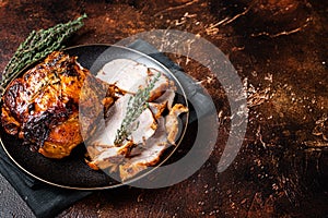 Roast rolled pork ham meat on plate with thyme. Dark background. Top view. Copy space