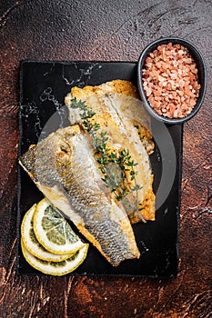 Roast sea bass fillet with lemon and thyme, seabass fish. Dark background. Top view