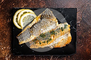 Roast sea bass fillet with lemon and thyme, seabass fish. Dark background. Top view