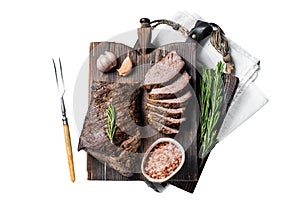 Roast and sliced tri tip beef steak on a wooden board with herbs. Isolated, white background.