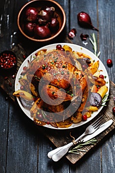 Roast whole chicken with roast vegetables on plate on a table