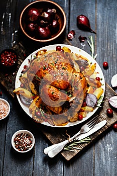 Roast whole chicken with roast vegetables on plate on a table