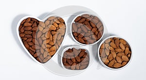 Roasted almond in heart shape bowl on white background