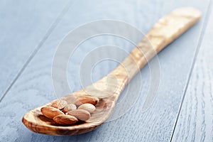 Roasted almonds in spoon on blue wooden table