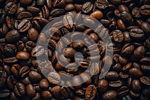 Roasted Arabic coffee beans are strewn on the table. Background formed by grains of roasted coffee close-up. Roasted