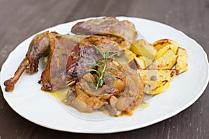 Roasted or baked Guinea fowl served with baked potatoes and sweet onion with apples and raisins.