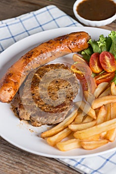 Roasted beef meat steak and sausage with french fries.